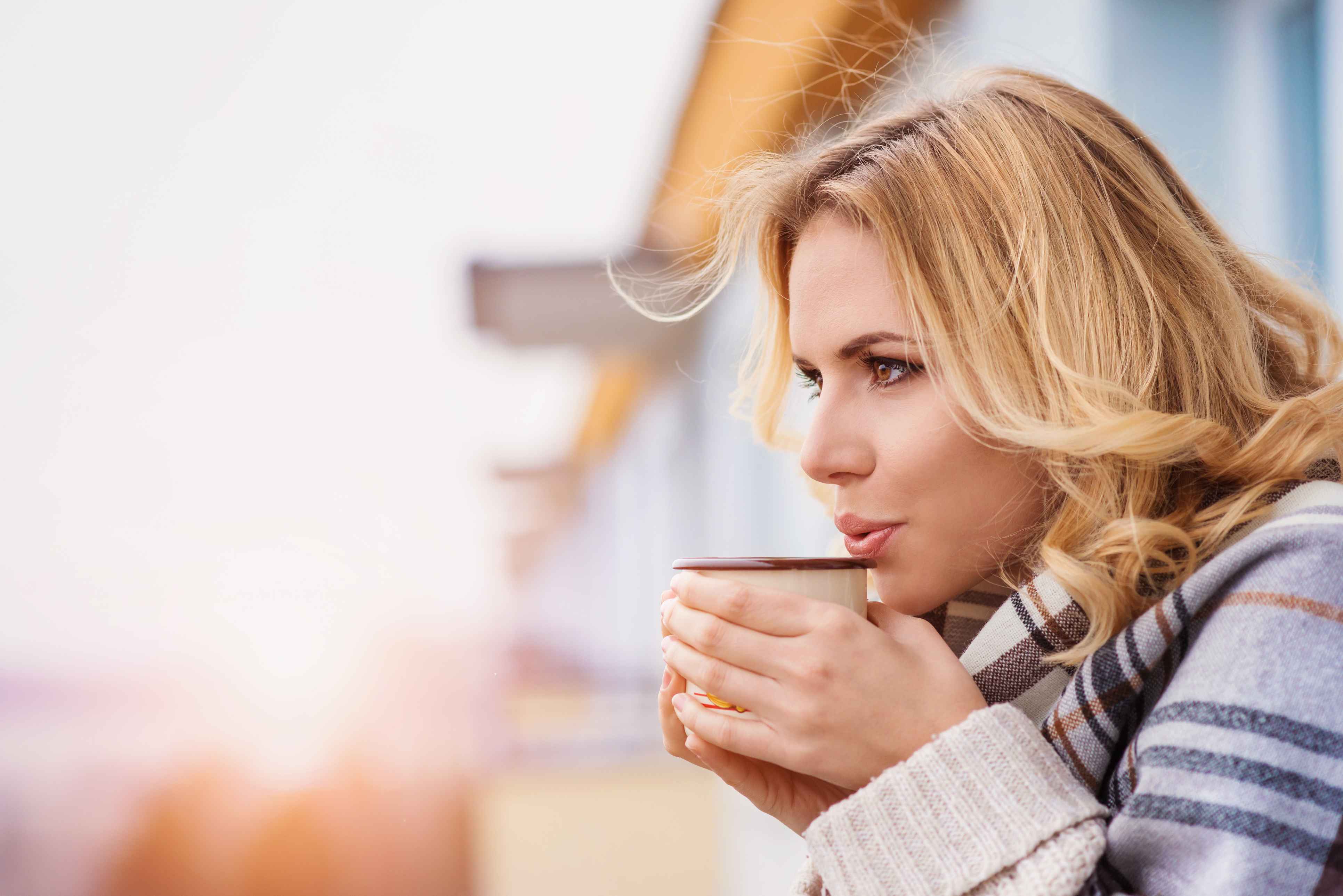 Frau draußen mit Tasse in den Händen