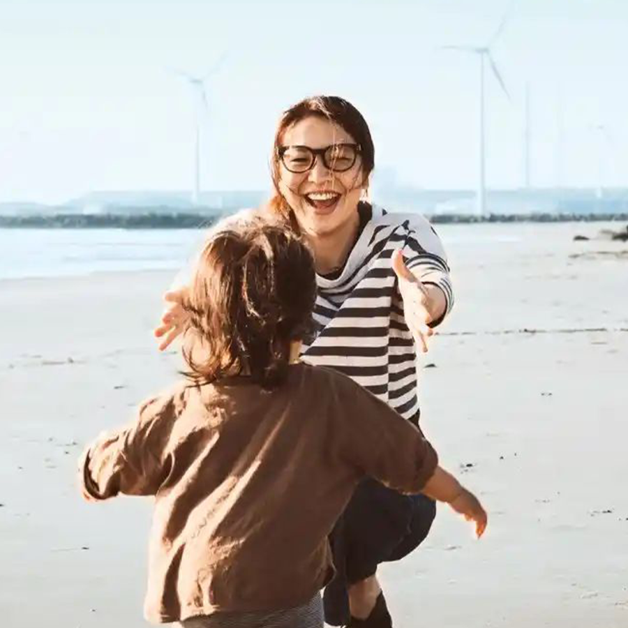 Mutter und Kind am Strand- im Hintergrund Windräder