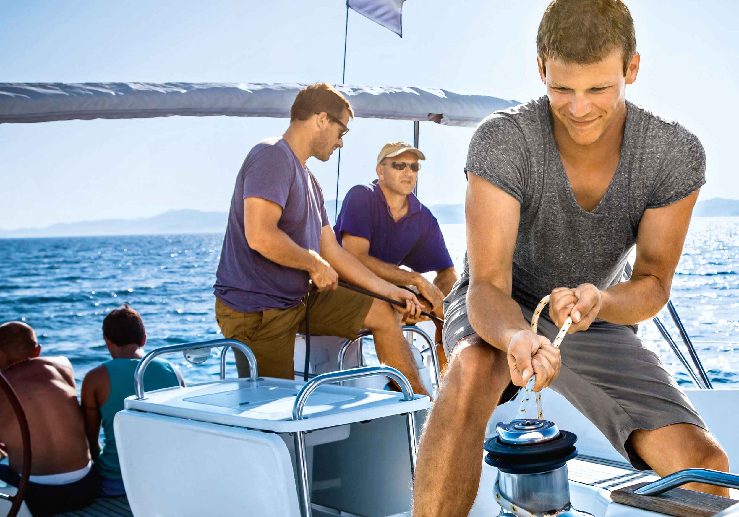 Drei Männer ziehen ein Seil am Segelboot fest