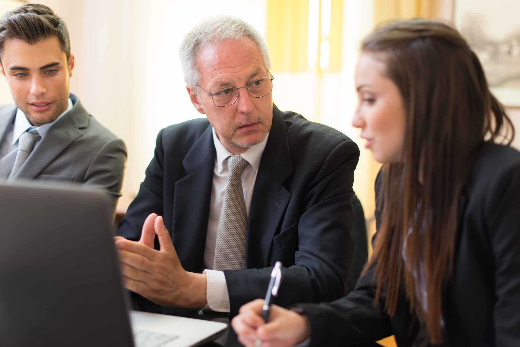 Drei Angestellte sitzen am Bürotisch und sprechen miteinander